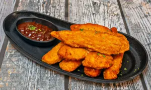 Chrupiące kotlety z piersi kurczaka podane z sosem barbecue. Idealne na przekąskę lub danie główne.