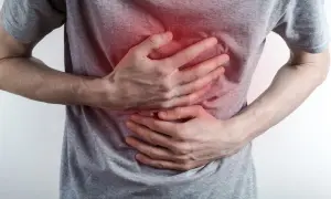 Osoba trzyma się za bolącą klatkę piersiową, z zaczerwienionym obszarem bólu.