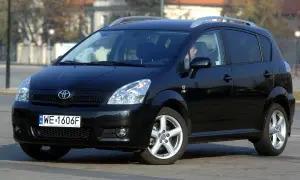 Czarna Toyota Corolla Verso z relingami dachowymi, zaparkowana na ulicy.