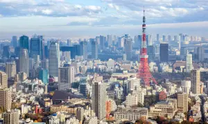 Rozległy krajobraz tokio miasto z wieżą Tokyo Tower na pierwszym planie i licznymi drapaczami chmur w tle.