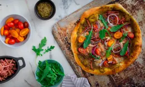 En läcker pizza bianco med parmaskinka, ruccola, körsbärstomater och rödlök. Perfekt för en mysig kväll!