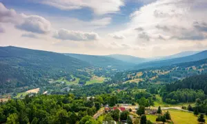 Widok na dolinę z domami i lasami, gdzie są Góry Izerskie.