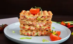 Gestapelte Sandwiches mit geschmolzenem Käse und Gemüse, perfekt für kontaktgrill rezepte. Garniert mit Tomaten und Frühlingszwiebeln.