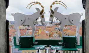 Dwa mechaniczne koziołki poznańskie, symbol miasta, na tle dachu ratusza.