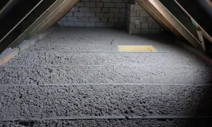 Izolacja z celulozy na poddaszu, widoczne drewniane krokwie i otwór.