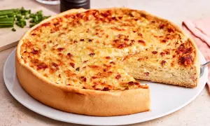 Ein goldbrauner Zwiebelkuchen mit Speck, bereit zum Servieren. Ein Stück fehlt, was Lust auf mehr macht. Perfekt für ein Zwiebelkuchen Rezept.