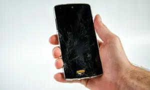 Dłoń trzyma pęknięty telefon, który nie chce się włączyć.