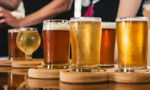 Assaggio di birra danese: bicchieri di diverse birre ambrate e dorate, con schiuma cremosa, su un vassoio di legno.