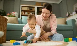 Mama z dzieckiem bawią się pociągiem na dywanie. Każde dziecko to skarb, a inwestycja 12 tys na dziecko to piękny początek.