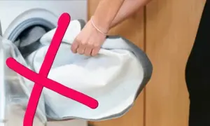 Rote Kreuze über einem weißen Wäschestück, das aus einer Waschmaschine genommen wird. Das zeigt, was darf nicht in den trockner.