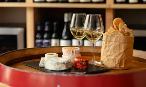 Dégustation de fromages et de pain frais avec deux verres de vin blanc, une scène parfaite pour un vin Paris.