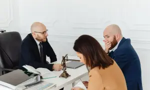 Prawnik omawia testament za opiekę i zachowek z parą. Mężczyzna wygląda na zmartwionego.