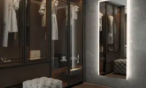 En spegel med belysning bakom spegel ger ett mjukt ljus i en lyxig walk-in-closet med kläder och accessoarer.