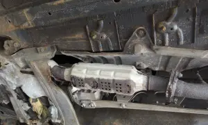 Vue du dessous d'une voiture montrant un catalyseur rouillé, nécessitant un nettoyage catalyseur pour améliorer les performances.