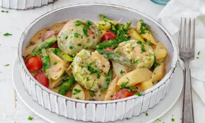 Spargel mal anders: cremiger Eintopf mit Klößen, Kartoffeln, Kirschtomaten und grünen Bohnen, garniert mit Petersilie.