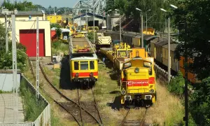 Dwie żółte lokomotywy, jedna z napisem "PKP Energetyka", stoją na torach w słoneczny dzień.