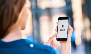 Kobieta z nowym telefonem, na ekranie którego widnieje logo aplikacji IKO. Szybko dowiesz się, jak zalogować się do aplikacji IKO na nowym telefonie.