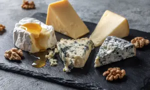 En ostbricka med brie, blåmögelost och en bit ost som påminner om ost comte, garnerad med valnötter och honung.