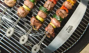 Spiedo di carne mista succulenta e verdure grigliate su una griglia Weber.