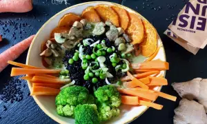 Bunter Reisschüssel mit schwarzem Reis, Süßkartoffeln, Brokkoli, Karotten, Erbsen und Pilzen in cremiger Sauce. Ein Gericht, das reich an Kohlenhydraten ist.