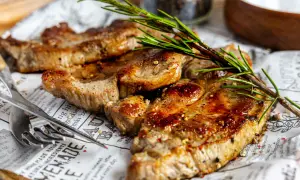 Saftiges Nackensteak im Backofen, perfekt gewürzt und mit Rosmarin garniert, liegt auf Zeitungspapier.
