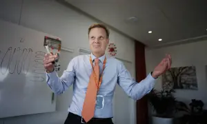 Swedbank vd med orange slips och namnskylt håller en penna vid en whiteboard.