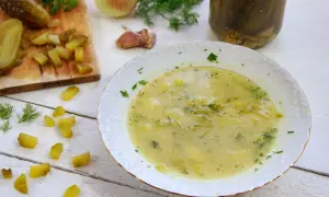 Zupa ogórkowa przepis babci, pachnąca koperkiem i czosnkiem, z kawałkami ogórków na desce i w słoiku.