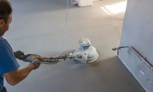 Lavoratore leviga massetto con monospazzola. Preventivo costo rifacimento massetto e pavimento.