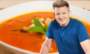 Gordon Ramsay obok talerza zupy pomidorowej z grzankami i bazylią.