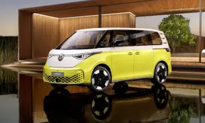 Nowy, elektryczny VW ID. Buzz w dwukolorowym malowaniu, z białym dachem i żółtym nadwoziem, stoi na tle nowoczesnej architektury.