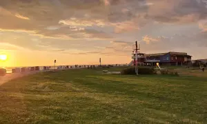 Sonnenuntergang am Husum Strand mit Strandkörben, einem Spielplatz und einem bunten Gebäude.