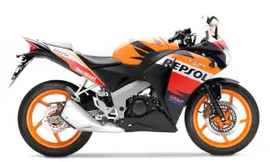 Pomarańczowo-czarny motocykl Honda CBR 125R w barwach Repsol, gotowy do jazdy z mocą V-max.
