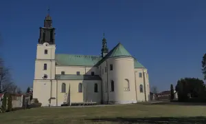 Bazylika w Gidlach z charakterystyczną wieżą i zielonym dachem, na tle błękitnego nieba.