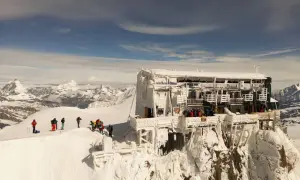 Die Capanna Margherita thront eisbedeckt auf einem Berggipfel. Bergsteiger genießen die Aussicht auf die verschneite Alpenlandschaft.