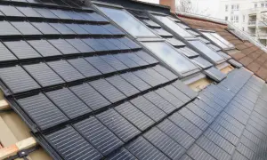 Dach renovieren kosten: Solarmodule werden auf einem Dach mit Dachfenstern installiert.