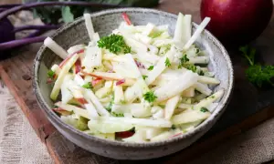 Kohlrabi Salat mit Apfelstücken und frischer Petersilie in einer rustikalen Schüssel.