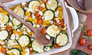 Gebackener Feta mit Zucchini, Kirschtomaten und gelber Paprika in einer Auflaufform, bereit zum Servieren.
