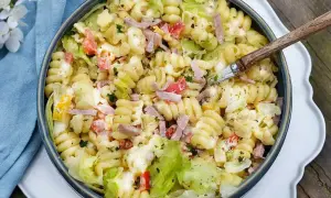 En stor skål med pastasallad med skinka, grönsaker och en krämig dressing. Perfekt för en sommarlunch!