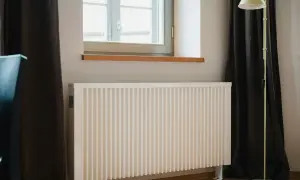 Vitt element med ribbad front, perfekt för att bygga elementskydd. En golvlampa står bredvid.