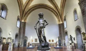 Bronzene Statue von David in Florenz, ein Meisterwerk der Renaissance, steht in einem Museumssaal unter kunstvollen Gewölben.
