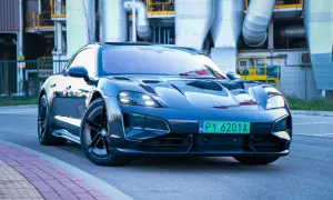 Elegancki Porsche Taycan Turbo S błyszczy na tle przemysłowej architektury.