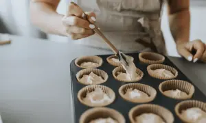 En person fyller muffinsformar med smet. Bra baka tips för perfekta muffins.