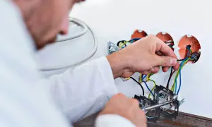 Elektryk podczas wymiany instalacji elektrycznej w mieszkaniu podłącza przewody do puszek.