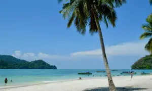 Rajskie **Filipiny plaże** z palmami, turkusową wodą i łodziami. Ludzie kąpią się i odpoczywają na piasku.