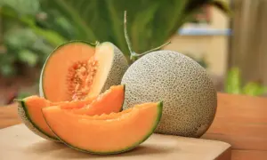 Melón entero y cortado, mostrando su pulpa naranja y semillas. Un festín de las propiedades del melón.