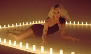 Miley Cyrus w stylizacji na "endless summer vacation" leży wśród rozświetlonych lamp.