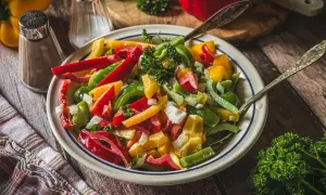 Bunter Paprika Salat mit Zwiebeln und Petersilie, serviert in einer Schüssel mit zwei Löffeln.