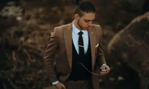 Stilberatung für Senioren: Mode ab 60. Ein Mann im eleganten braunen Anzug mit Weste und Krawatte hält eine Taschenuhr.
