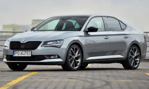 Elegancki, szary Skoda Superb 2024 z czarnym dachem i przyciemnianymi szybami, zaparkowany na parkingu.