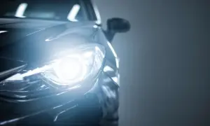 Phare avant d'une voiture allumé, prêt à affronter la pluie. Quelle feu mettre quand il pleut ? Les feux de croisement sont essentiels pour la visibilité.